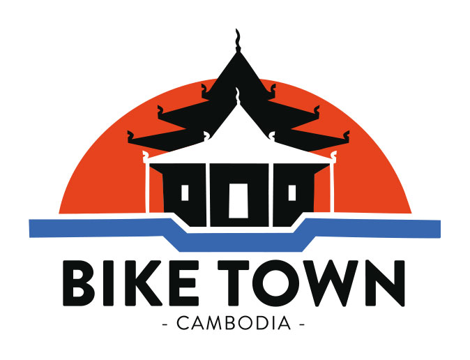 Illustrated logo featuring a Cambodian temple with a dark orange half sun rising behind it. Below the temple and sun is a blue line shaped like bicycle handlebars. The text beneath reads: 'Bike Town – Battambang Tours –'